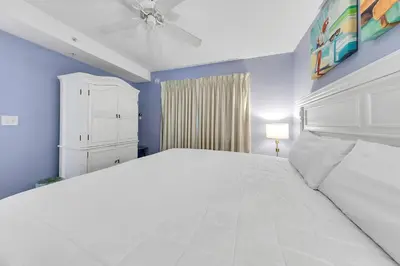 a bedroom with a large white bed and blue walls at Emerald Beach 1035 in Panama City Beach