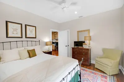 a bedroom with a large bed and a chair at Magnolia Cottage in Inlet Beach