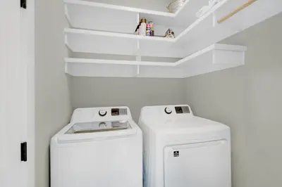 a laundry room with a washer and dryer and shelves at Magnolia Cottage in Inlet Beach