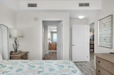 a white bedroom with a bed and a bathroom at Aqua Resort 2103 in Panama City Beach