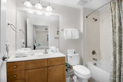 a bathroom with a sink and a toilet and a mirror at Aqua Resort 2103 in Panama City Beach