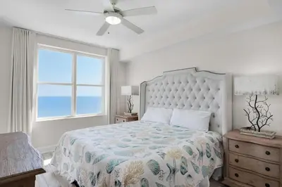 a bedroom with a bed with a ceiling fan and a window at Aqua Resort 2103 in Panama City Beach