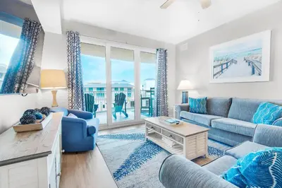 a living room with a couch and a table at Calypso 3-406 - Paradise by the Pier in Panama City Beach