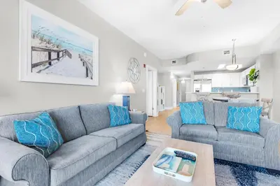 a living room with two couches and a table at Calypso 3-406 - Paradise by the Pier in Panama City Beach
