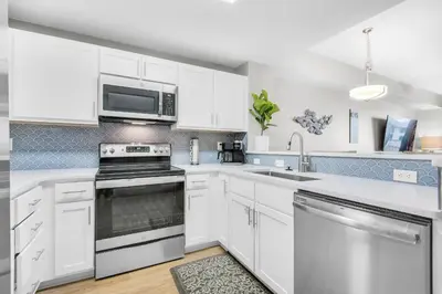 a kitchen with white cabinets and a stove top oven at Calypso 3-406 - Paradise by the Pier in Panama City Beach