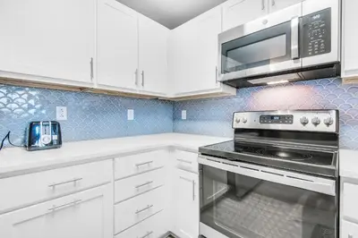 a kitchen with white cabinets and a microwave at Calypso 3-406 - Paradise by the Pier in Panama City Beach