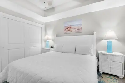 a white bedroom with a white bed and two lamps at Calypso 3-406 - Paradise by the Pier in Panama City Beach