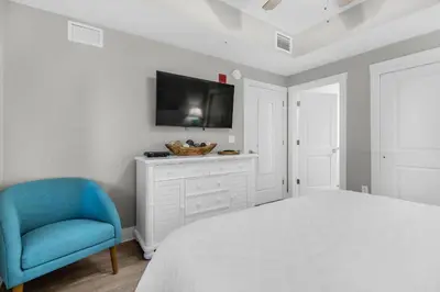 a bedroom with a bed and a blue chair at Calypso 3-406 - Paradise by the Pier in Panama City Beach
