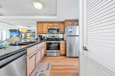 a kitchen with wooden cabinets and stainless steel appliances at Edgewater Tower 2-404 in Panama City Beach