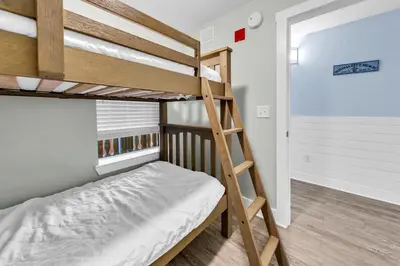 a bunk bed in a small room with a ladder at Calypso 3-202 - The Sea Suite in Panama City Beach