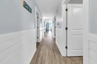 a hallway with white doors and wood floors at Calypso 3-202 - The Sea Suite in Panama City Beach