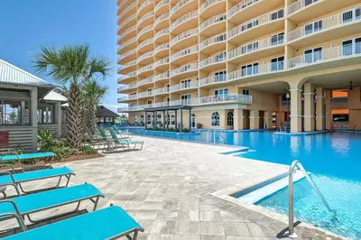 a hotel swimming pool with blue benches in front of a building at Calypso 3-202 - The Sea Suite in Panama City Beach