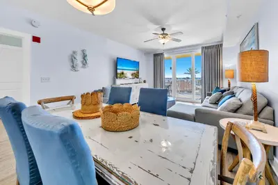 a living room with a table and blue chairs at Calypso 3-202 - The Sea Suite in Panama City Beach