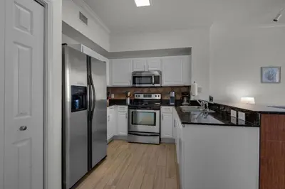 a kitchen with white cabinets and a stainless steel refrigerator at Tidewater 3013 in Panama City Beach