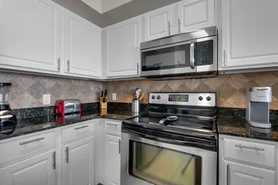 a kitchen with white cabinets and a stove and microwave at Tidewater 3013 in Panama City Beach
