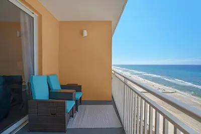 a room with a balcony with a view of the beach at Splash 603E in Panama City Beach