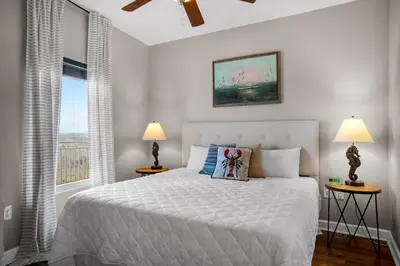 a bedroom with a bed with two lamps and a window at Splash 603E in Panama City Beach