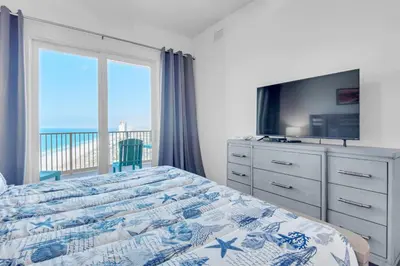 a bedroom with a bed with a television and a balcony at Calypso 3-2307 in Panama City Beach
