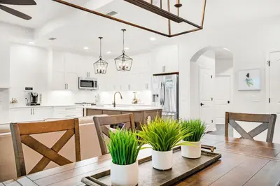 a kitchen with white cabinets and a wooden table with plants at Pearl Flamingo in Panama City Beach
