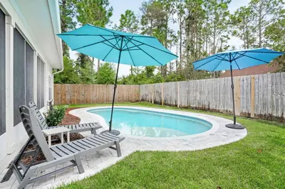 a pool with two chairs and two umbrellas at Pearl Flamingo in Panama City Beach