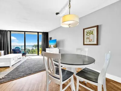 a dining room with a table and chairs and a living room at Edgewater Tower 1-305 in Panama City Beach