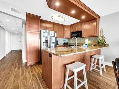 a kitchen with wooden cabinets and a counter with stools at Edgewater Tower 1-305 in Panama City Beach