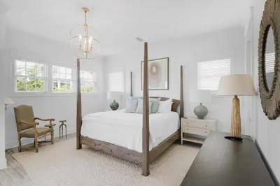 a white bedroom with a bed and a chair at Churchill Dunes in Inlet Beach