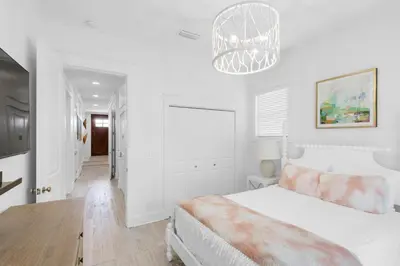 a white bedroom with a bed and a chandelier at Churchill Dunes in Inlet Beach
