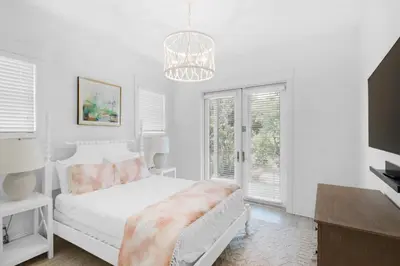 a white bedroom with a bed and a chandelier at Churchill Dunes in Inlet Beach