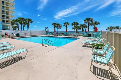a swimming pool with blue chairs and palm trees at Gulf Highlands 116H in Panama City Beach
