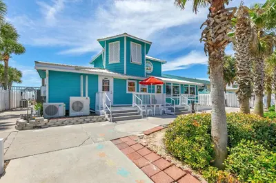 a blue house with palm trees in front of it at Gulf Highlands 116H in Panama City Beach