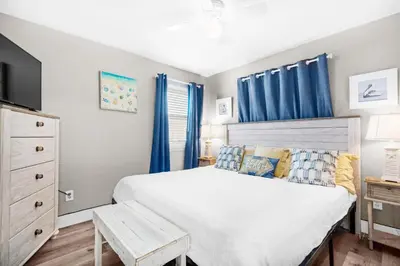 a bedroom with a large bed with blue curtains at Gulf Highlands 116H in Panama City Beach