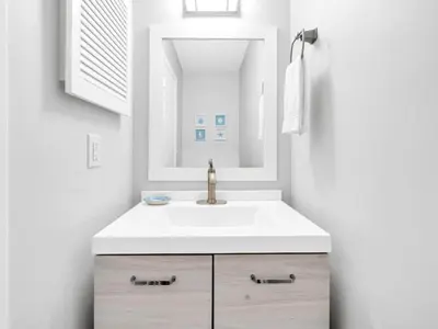 a white bathroom with a sink and a mirror at Portside R4 in Panama City Beach