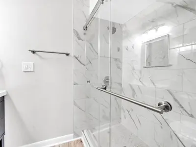 a white bathroom with a shower with a glass door at Portside R4 in Panama City Beach