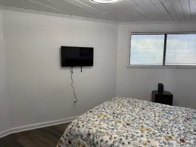 a bedroom with a bed and a flat screen tv on the wall at Peaceful Lydia Hide-O-Way - New Pool & Near Beach, Breakfast, Spa & Go-Karts! in Panama City Beach