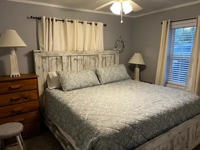 a bedroom with a bed and a dresser and a window at The Fifth Promise - A Cozy Lakehouse Retreat in Chipley