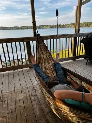 a person laying in a hammock on a deck at The Fifth Promise - A Cozy Lakehouse Retreat in Chipley