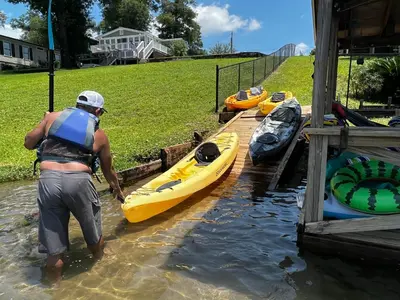 a man standing in the water next to a group of kayaks at The Fifth Promise - A Cozy Lakehouse Retreat in Chipley