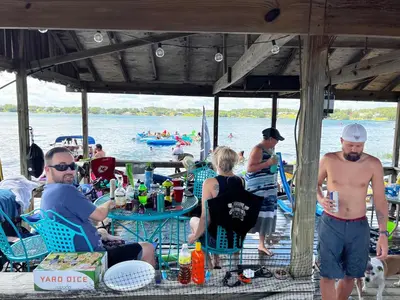 a group of people sitting at a table near the water at The Fifth Promise - A Cozy Lakehouse Retreat in Chipley