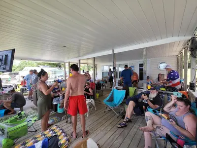 a group of people sitting and standing in a covered deck at The Fifth Promise - A Cozy Lakehouse Retreat in Chipley