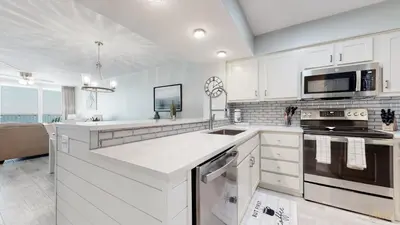 a kitchen with white cabinets and a stove top oven at Beachfront - Renovated - Gulf view Bedroom - FLPCB5 in Panama City Beach