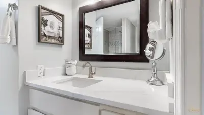 a white bathroom with a sink and a mirror at Beachfront - Renovated - Gulf view Bedroom - FLPCB5 in Panama City Beach