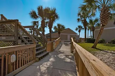 a wooden staircase leading to a house with palm trees at Beachfront - Renovated - Gulf view Bedroom - FLPCB5 in Panama City Beach