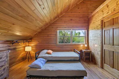 a bedroom with two beds in a wooden cabin at Fun fishing river cabin 23mi to beach with private dock 3BD 2BA in Youngstown
