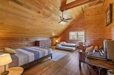 a log cabin bedroom with a bed and a couch at Fun fishing river cabin 23mi to beach with private dock 3BD 2BA in Youngstown