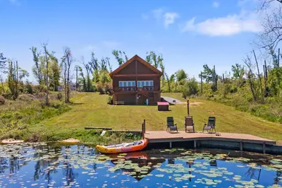 a house with a boat in the water in front of it at Fun fishing river cabin 23mi to beach with private dock 3BD 2BA in Youngstown