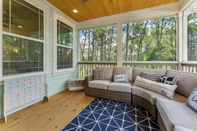 a screened porch with a couch and windows at Hidden Tides in Rosemary Beach