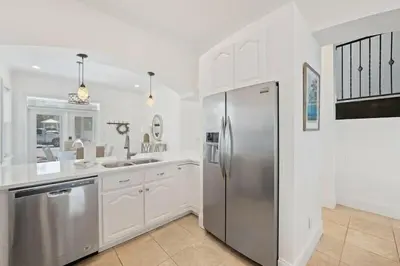 a kitchen with white cabinets and a stainless steel refrigerator at Seacrest Getaway in Rosemary Beach