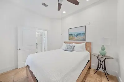 a white bedroom with a bed and a table at Seacrest Getaway in Rosemary Beach