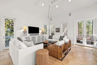 a living room with white furniture and a flat screen tv at Ocean Serenade in Rosemary Beach